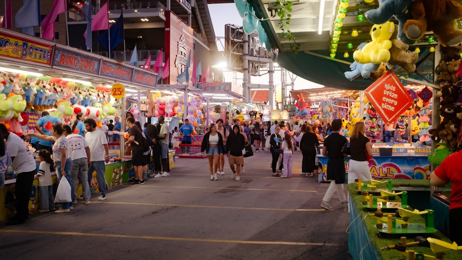 Carnival midway with game booths, prizes, and evening crowds
