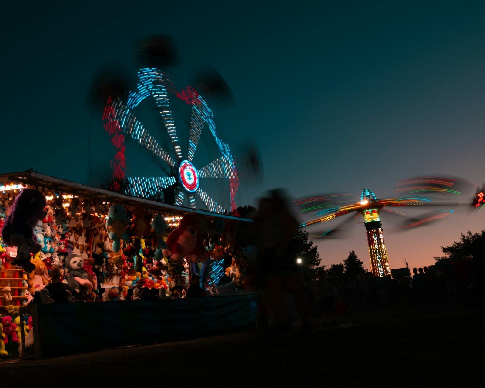 Carnival prize booth and lit rides at night