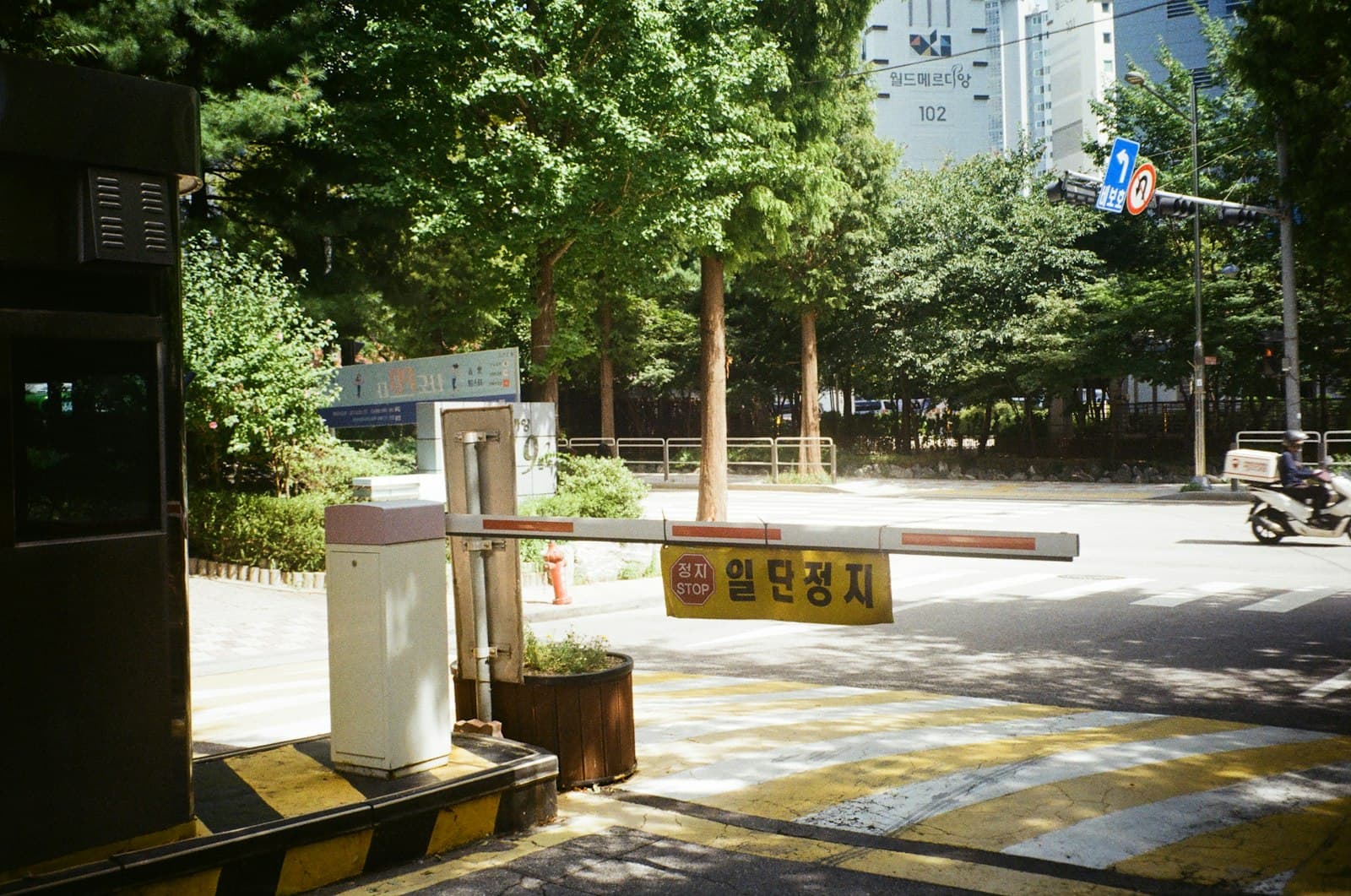 White boom barrier with red stripes at a tree-lined lot entrance