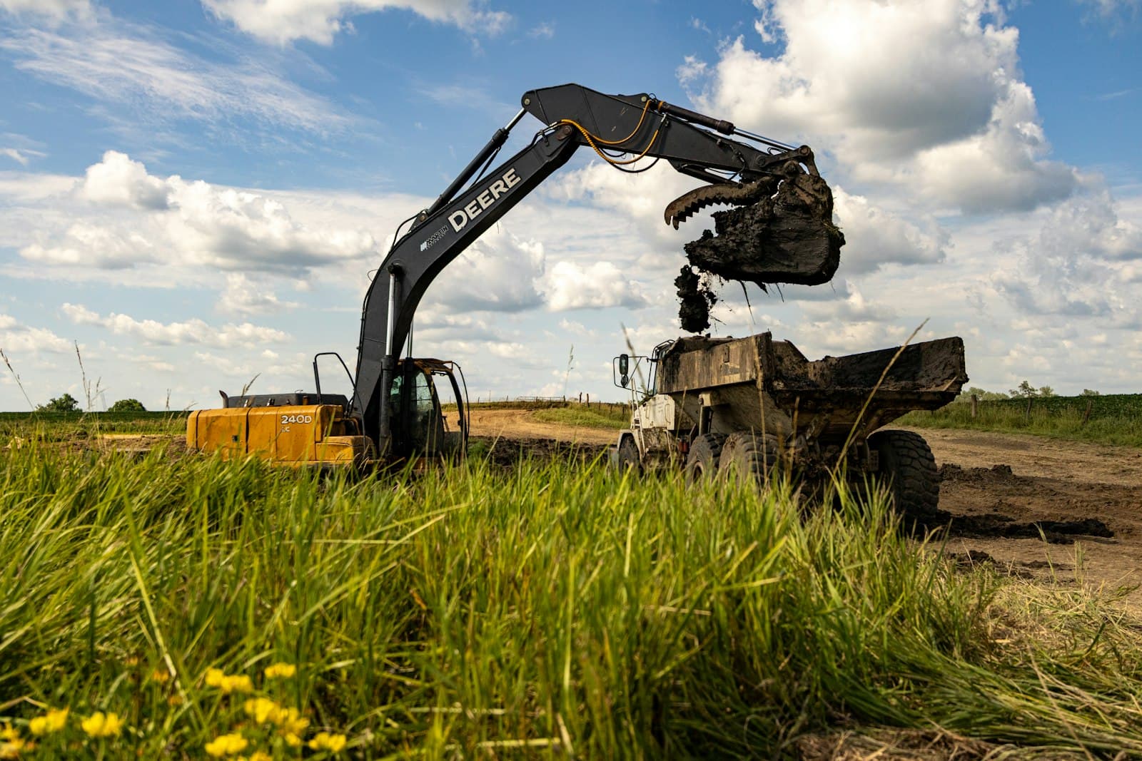 Heavy excavator and dump truck on a public-works style equipment yard