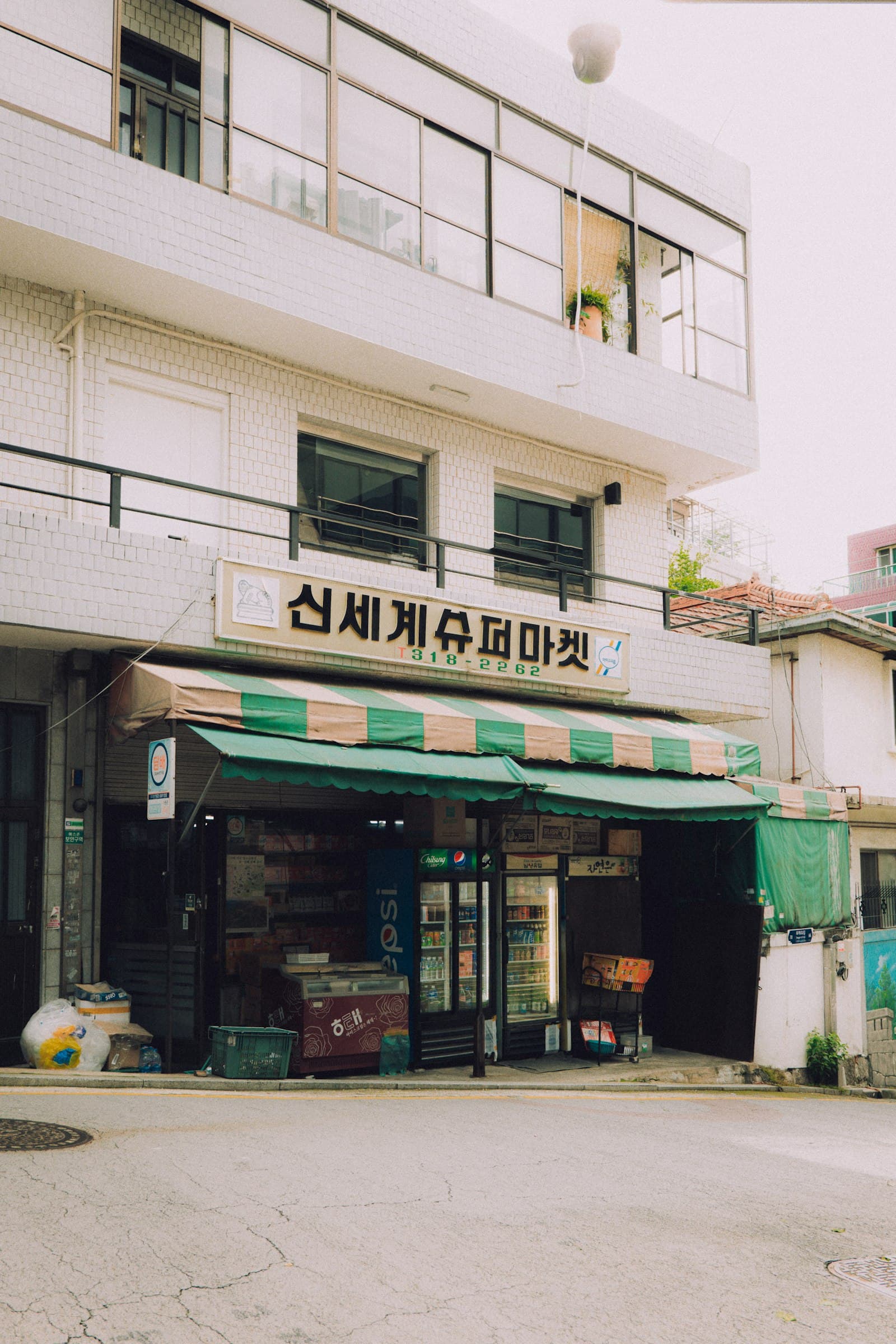 Corner neighborhood supermarket storefront with awning and sidewalk coolers