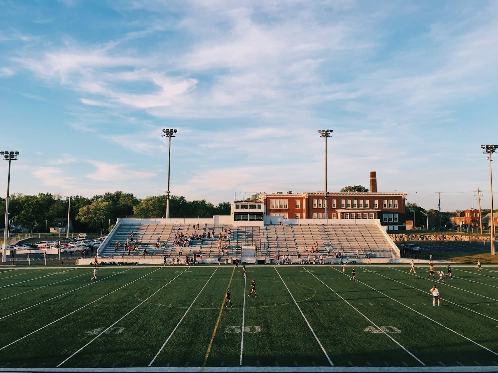 School athletic field with turf, bleachers, and stadium lights