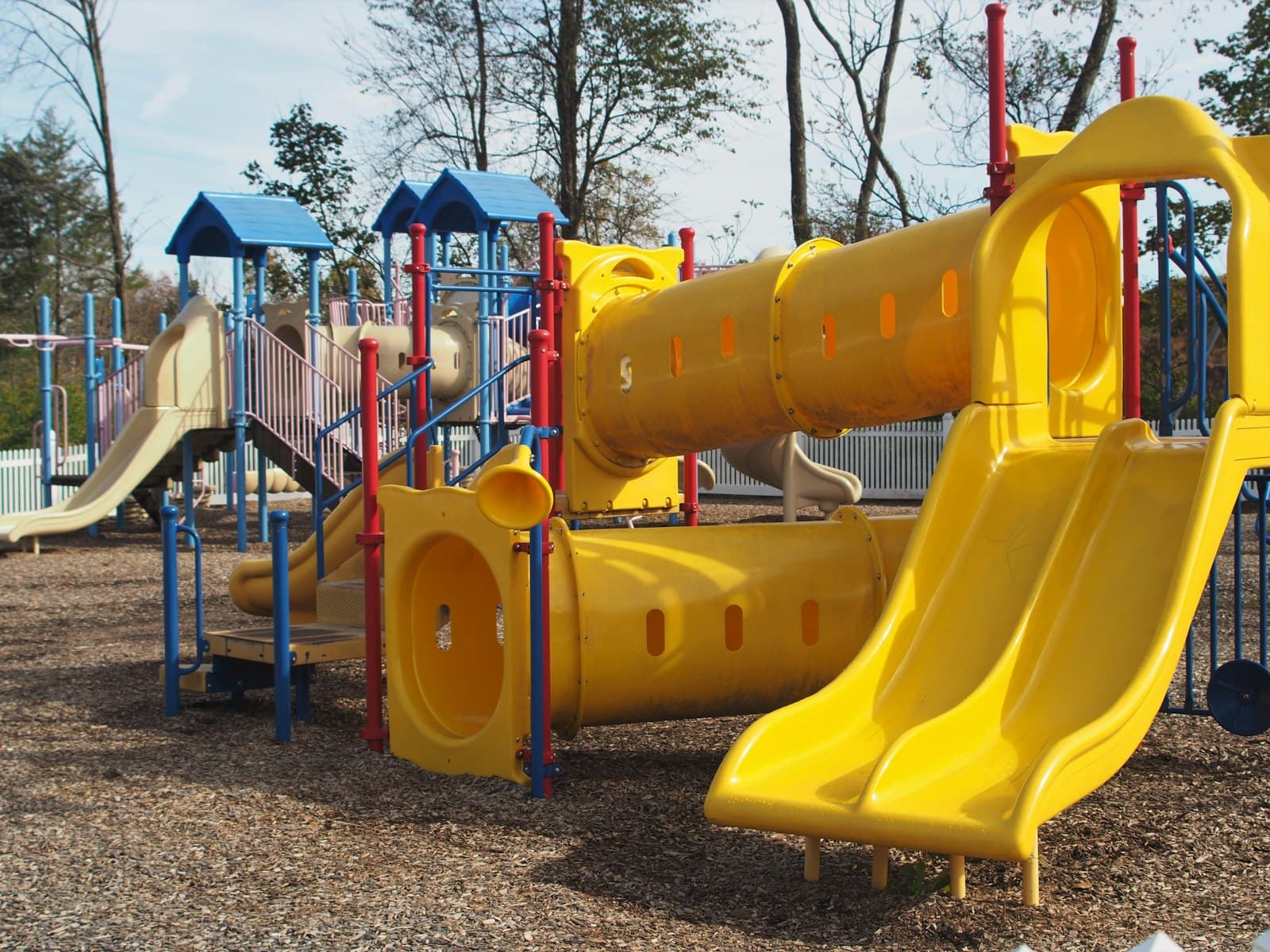 Empty outdoor playground with yellow slides and climbing structure